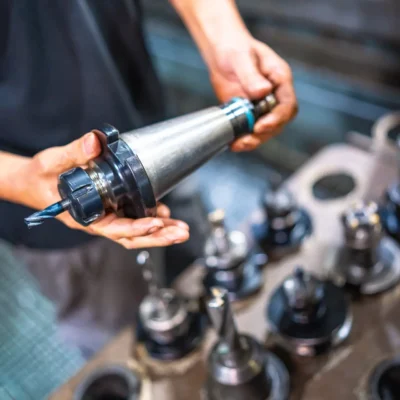Vertical photo of an operator holding the head of a milling machine in a cnc factory